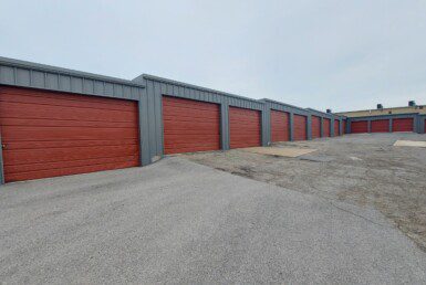 A row of red garage doors on a cloudy day.