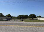 Fenced area with trees and buildings visible.