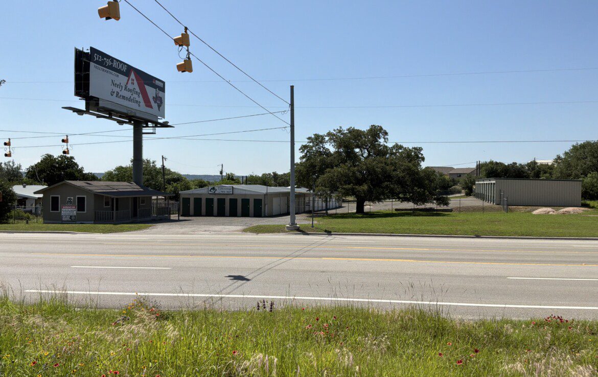 Roadside scene with billboard and storage units.